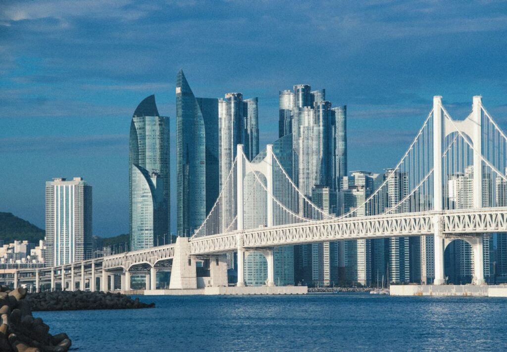 Stunning skyline of Busan with Gwangan Bridge at day, showcasing modern architecture against blue skies.