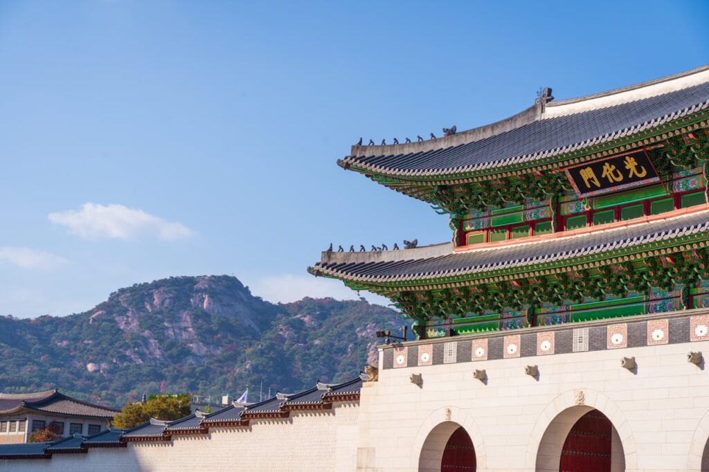 View of Gyeongbokgung Palace with traditional Korean architecture set against a mountain backdrop on a sunny day.